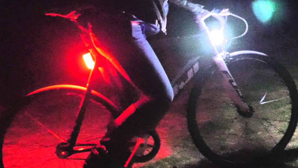 Image showing front and rear lights mounted on a bike in the dark.